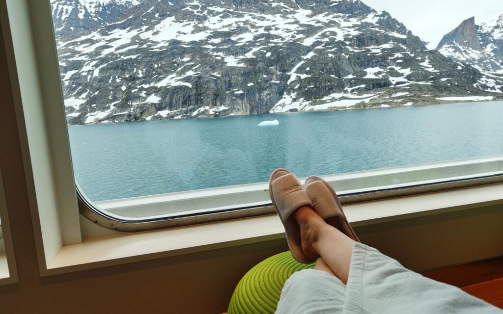 Blick aus der Sauna der HANSEATIC spirit auf einen Fjord und verschneite Berge.